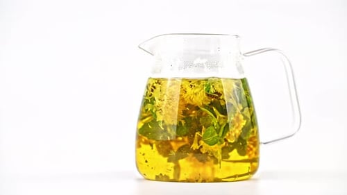 Glass Pitcher of Herbal Tea Steaming on White