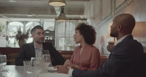 Three Businesspeople having a Meeting in a Restaurant using Laptop