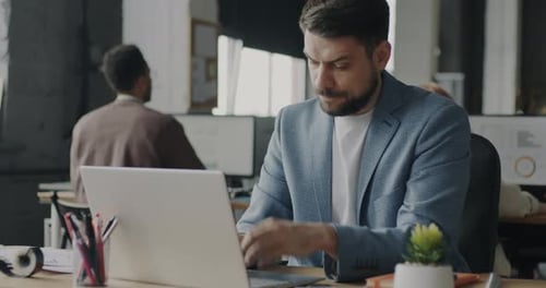 Frustrated Young Man Working with Laptop Typing Thinking About Business Problem in Office