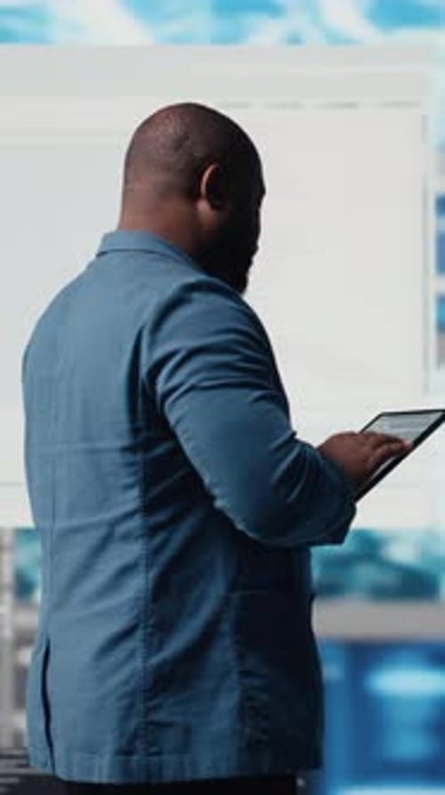 Vídeo vertical: un joven ingeniero profesional centrado en la programación con tabletas en un centro de innovación