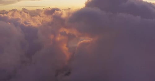 Vue aérienne survolant les nuages violets au coucher du soleil avec des reflets dorés
