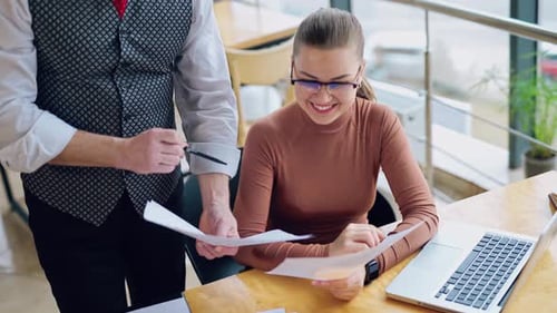 Businesswoman Reviews Documents with Coworker in Office