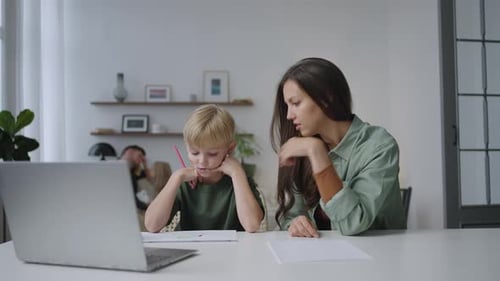 Woman Helping a Child With Homework at Home