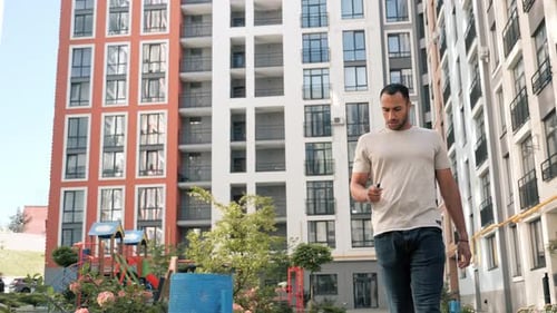 Man Using Phone While Walking in Urban Area