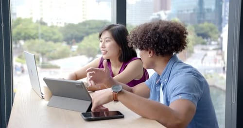 Collaborating on project, colleagues using tablets and smartphone in modern office