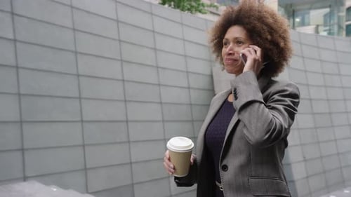 Businesswoman Walking, Talking on Phone and Drinking Coffee