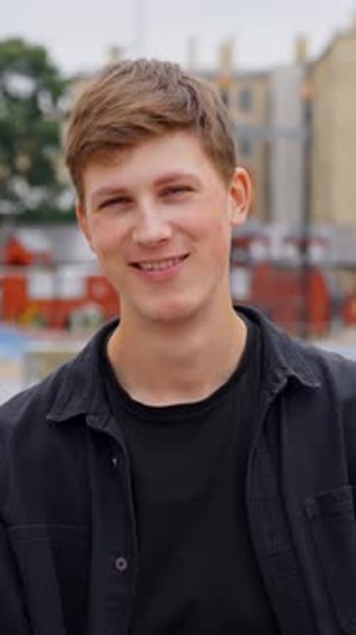 Jeune homme souriant profitant d'une journée ensoleillée en milieu urbain, vertical