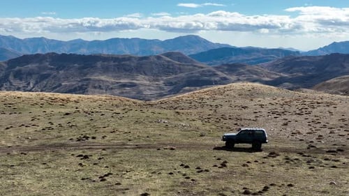 Aerial View Of Hills And Offroad Vehicle Driving On Mountain Road