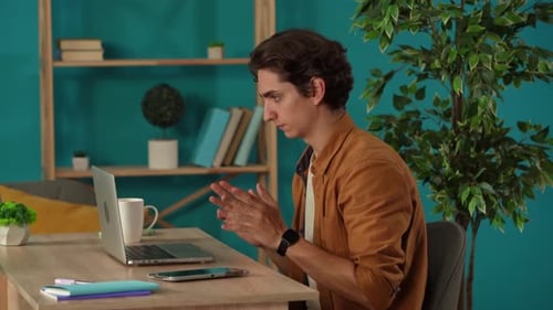 Medium Shot Capturing a Man Having a Videocall Talking to Somebody on a Laptop in His Home Office