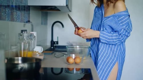 Sexy Girl Preparing Traditional Breakfast With Eggs. Close Up Woman Hands Breaking Eggs Into Glas...