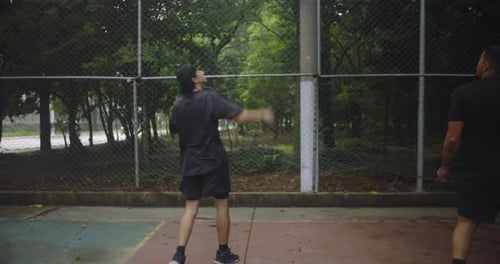 Hispanic man throwing basketball into hoop on outdoor court during casual game with friends,