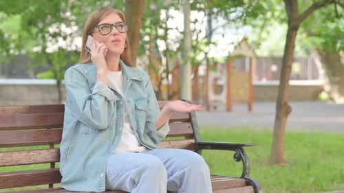 Young Woman Talking on a Smartphone in a Park Setting