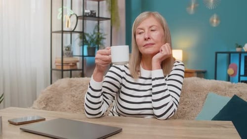 Mature Woman Happily Closing Laptop After Completing Important Task Smiling and Relaxing at Table