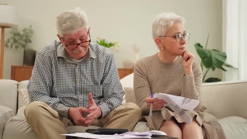 Concerned Couple Managing Finances on Sofa at Home