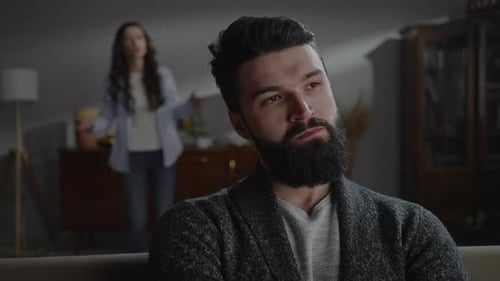 Man Rolling Eyes as Woman Argues in Background