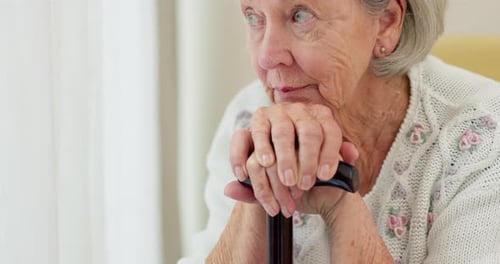 Elderly Woman Holding Cane While Sitting Indoors