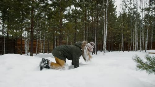Teen Girl Playing and Tossing Snow in Winter Forest