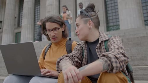 Students Collaborating on Laptop on College Steps