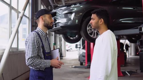 Mechanic and Customer Talk in Auto Repair Shop