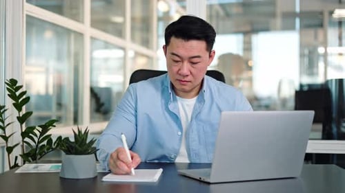 Young Adult Working at a Laptop in an Office