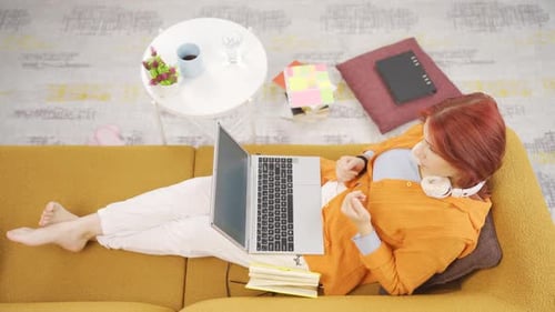 Woman Lies on Couch Typing on Laptop