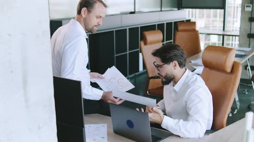 Meeting Between Two Professionals Discussing Project Details in a Modern Office Environment During