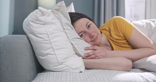 Woman Resting on Sofa with Pillows Indoors