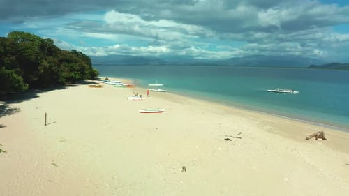Beach with boats and person enjoying holiday on sandy beach in tropical island.