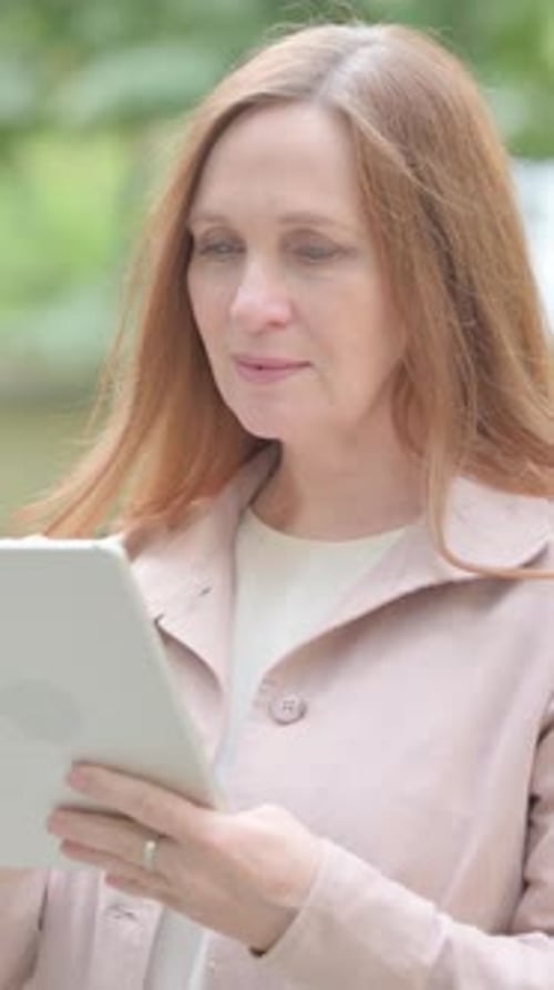 Woman with Tablet Device Outside in City Park