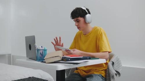 A Teenager is on a Video Call Showing His Notebook to Someone on the Laptop Screen It Appears to Be