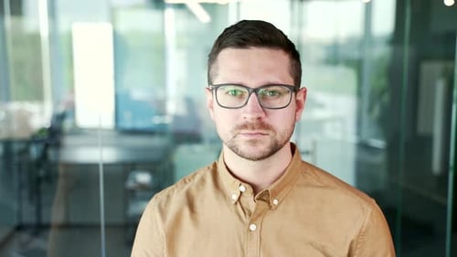 Nahaufnahme eines seriösen, erfolgreichen Geschäftsmannes in Hemd und Brille, der am Arbeitsplatz steht
