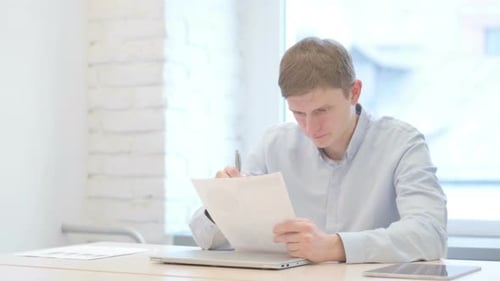 Young Businessman Working on Documents in Office