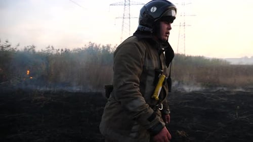 Firefighter Walking Through a Charred Rural Field