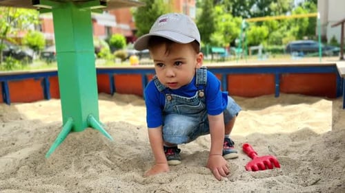 Un adorable bébé caucasien est assis dans un bac à sable.