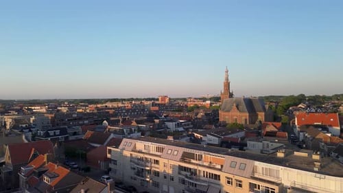 Drone view of a picturesque European town with a towering church, red-roofed houses, winding streets