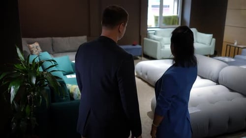 Back View Serious Man and Woman Talking Standing in Furniture Shop Indoors