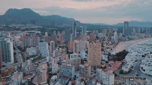 Modern coastal town next to the blue sea at golden pink sunset. Tall buildings and high skyscrapers.