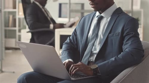 Man in Suit Typing on Laptop in Office