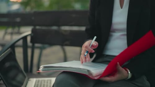 Woman Reviews Documents and Uses Laptop in City
