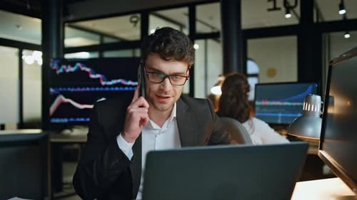 Un homme d'affaires souriant parle d'un smartphone sur Investment Graph. Un vendeur prospère qui travaille tard | Consult