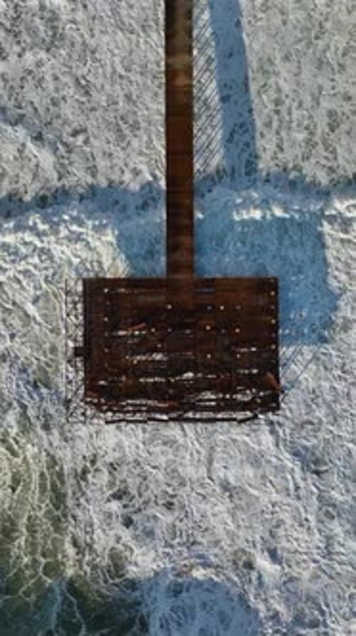 Vertical Video Aerial Insight Captivating Morning Storm's Waves Crushing a Wooden Pier