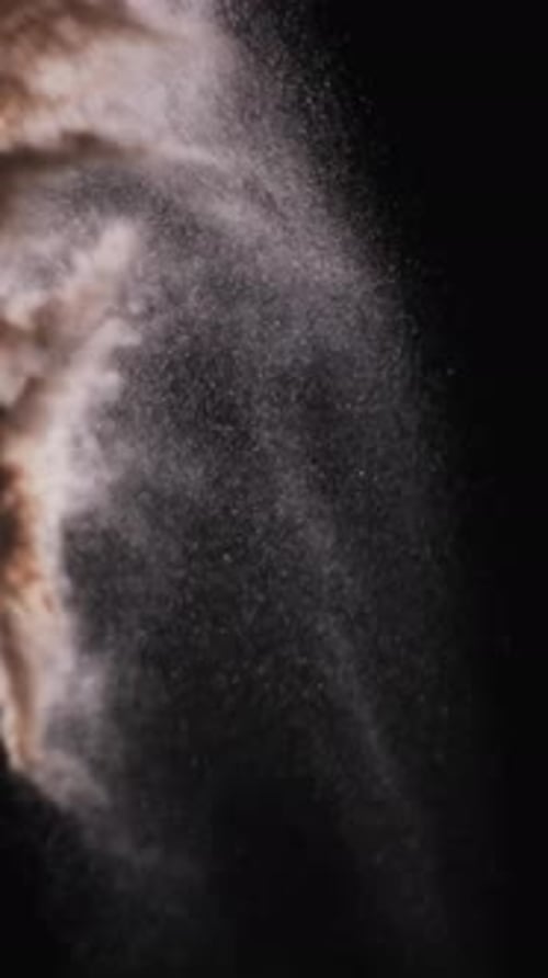 Vertical video of white sand grains thrown in air and copy space on black background