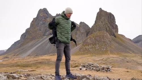 Man Removing Backpack on Rocky Mountain Landscape