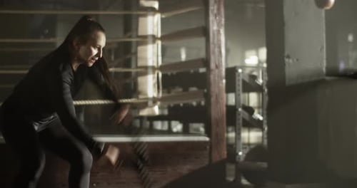 Strong Athletic Woman Training with Battle Rope in Gymnasium