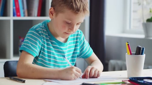 Boy is Doing His Homework at the Table Cute Child is Learning at Home with the Help of Textbooks and