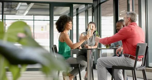 Team of diverse happy colleagues toasting drinks together at office