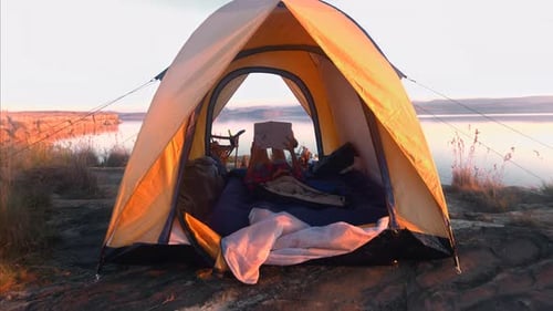 Woman Reads Book While Camping Near Lake