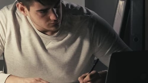 Young Adult Writing Notes at Desk