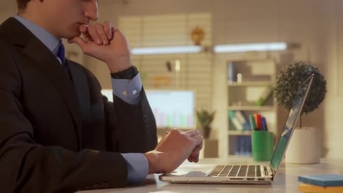 Seitenansicht eines jungen Mannes in einem Business-Anzug, der an einem Laptop arbeitet