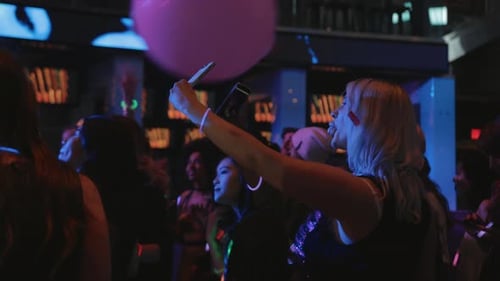 Crowd Dancing at Party with Neon Glow Sticks
